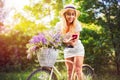 Beautiful young girl with vintage bicycle and flowers on city background in the sunlight outdoor. Royalty Free Stock Photo