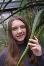 Portrait of happy beautiful young science student. Young girl in a greenhouse with tropic plants