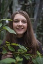 Portrait of happy beautiful young science student. Young girl in a greenhouse with tropic plants