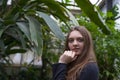 Portrait of happy beautiful young science student. Young girl in a greenhouse with tropic plants
