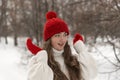 Portrait of happy beautiful young woman in knitted red hat and mittens and woolen sweater in winter park.Ladies knitwear Royalty Free Stock Photo