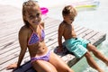 Portrait of happy biracial brother and sister sitting by the swimming pool Royalty Free Stock Photo