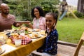 Portrait of happy biracial daughter at table having meal with parents in garden Royalty Free Stock Photo