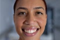 Portrait of happy biracial female doctor with nose piercing in corridor at hospital