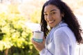 Portrait of happy biracial woman holding cup of coffee in sunny nature Royalty Free Stock Photo