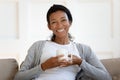 Portrait of happy biracial woman relax on couch drinking coffee Royalty Free Stock Photo