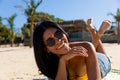 Portrait of happy biracial woman in sunglasses lying on towel on sunny beach smiling Royalty Free Stock Photo