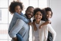 Happy biracial young couple parents giving piggyback ride to kids. Royalty Free Stock Photo