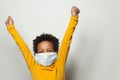 Portrait of happy black child boy in medical protective face mask holding hands up