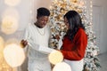 Portrait of happy black couple holding gift and standing near Christmas tree Royalty Free Stock Photo