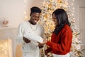 Portrait of happy black couple holding gifts and standing near Christmas tree Royalty Free Stock Photo