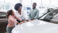 Portrait of happy black family buying new car, making choice in auto dealership Royalty Free Stock Photo