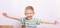 Portrait of happy blond boy child kid with arms open at the table Royalty Free Stock Photo