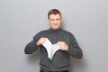 Portrait of happy blond mature man tearing paper sheet and smiling