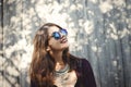 Portrait of happy boho girl in cool outfit and sunglasses smiling in sunlight. Stylish hipster girl posing in sunny street on Royalty Free Stock Photo