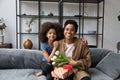 Portrait of happy bonding African American family holding wrapped gift.