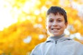 Portrait of happy boy in autumn city park. Posing on trees with yellow leaves. Bright sunlight and golden trees, fall season Royalty Free Stock Photo