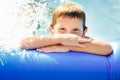 Portrait of a happy boy in a blue pool. A happy child swims in an inflatable pool in the garden on a sunny summer day Royalty Free Stock Photo