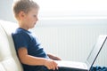 Portrait of happy boy playing with computer. Attractive kid with a laptop at home. Entertainment technology, futuristic Royalty Free Stock Photo