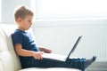 Portrait of happy boy playing with computer. Attractive kid with a laptop at home. Entertainment technology, futuristic Royalty Free Stock Photo