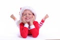 Portrait of happy boy in Santa hat and red Christmas costume lies, looks at camera and smiles. isolated on white Royalty Free Stock Photo