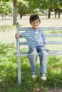 Portrait of a happy boy sitting on bench at park Royalty Free Stock Photo