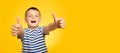 Portrait of happy boy in striped t-shirt showing thumbs up gesture on yellow background Royalty Free Stock Photo