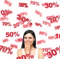 A portrait of a happy brunette lady in a white tank top who is dreaming about discounts. Red percentage marks are flying around th