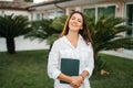 Portrait of a happy brunette woman smiling holding a tablet in the hands of a summer garden white shirt. The realtor