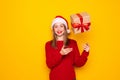 Portrait of happy brunette young woman in santa hat standing throwing gift boxes in air or catching presents, christmas shopping Royalty Free Stock Photo