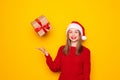 Portrait of happy brunette young woman in santa hat standing throwing gift boxes in air or catching presents, christmas shopping Royalty Free Stock Photo