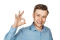 Portrait happy business man in blue shirt on a white isolated background showing sign okay