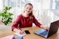 Portrait of happy business woman sitting at wood desk with notepat and laptop computer in modern office and looking at camera Royalty Free Stock Photo
