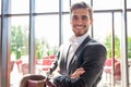 Portrait of happy businessman with arms crossed standing in office.