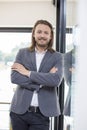 Portrait of happy businessman with arms crossed standing in office Royalty Free Stock Photo