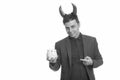 Portrait of happy businessman as devil pointing at piggy bank Royalty Free Stock Photo