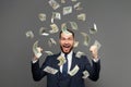 Portrait of happy businessman with heap of money on grey background