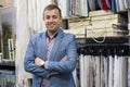 Portrait of happy businessman owner with crossed arms in interior fabrics store, background fabric samples. Small business home te Royalty Free Stock Photo