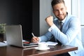 Portrait of happy businessman sitting at office desk, looking at camera, smiling Royalty Free Stock Photo