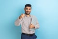 Businessman standing holding closed laptop or folder, has positive expression, pointing to camera. Royalty Free Stock Photo