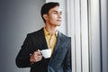 Portrait of Happy Businessman Standing by the Window in Office. Looking Away and Smiling. Dreaming for Success.