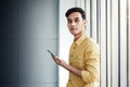 Portrait of Happy Businessman Standing by the Window in Office. Using Smartphone and Smiling Royalty Free Stock Photo