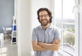 Portrait of a happy businessman in a T shirt and glasses standing by the office window Royalty Free Stock Photo