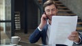 Happy businessman talking phone in office. Top manager discussing documents.