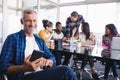 Portrait of happy businessman using mobile phone with team working in background Royalty Free Stock Photo