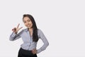 Portrait of happy businesswoman showing victory sign against gray background Royalty Free Stock Photo