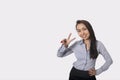 Portrait of happy businesswoman showing victory sign against gray background Royalty Free Stock Photo