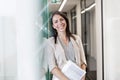 Portrait of happy businesswoman standing with documents by wall at office Royalty Free Stock Photo
