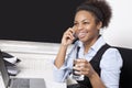 Happy businesswoman using cell phone in front of laptop at desk in office Royalty Free Stock Photo