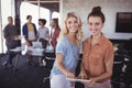 Portrait of happy businesswomen holding digital tablet with creative team Royalty Free Stock Photo